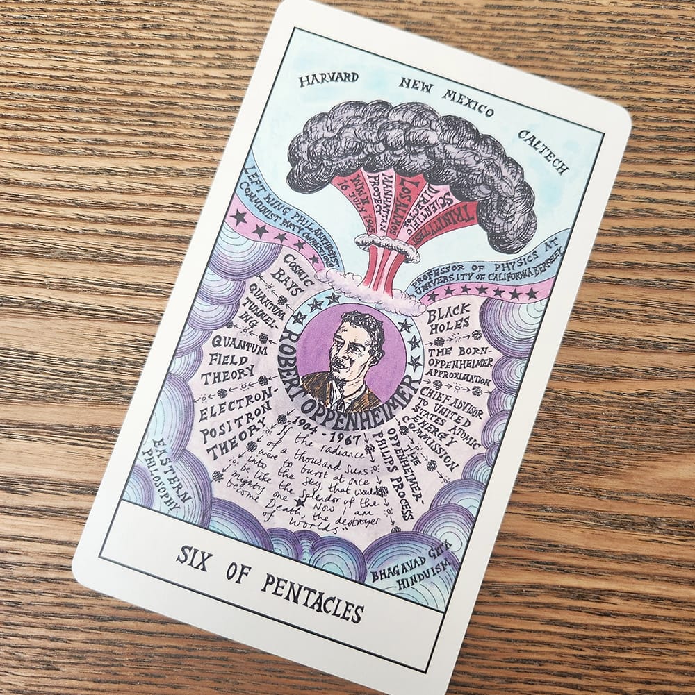 A six of pentacles tarot card showing a drawing of Oppenheimer and an atomic bomb explosion.